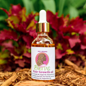 Bonitas hair oil in a clear dropper bottle with a gold collar, photographed against flowers